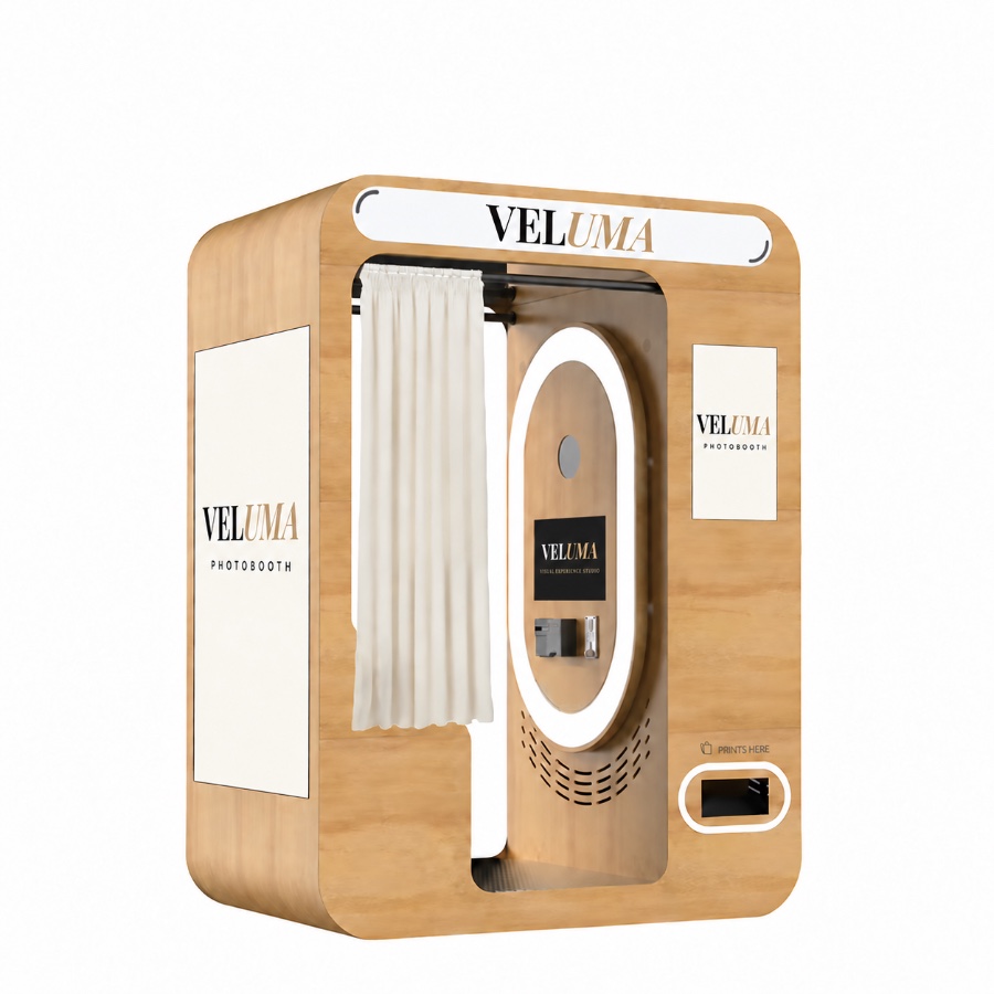 The Veluma enclosed photo booth cabin in light oak with a curtained entry and print slot