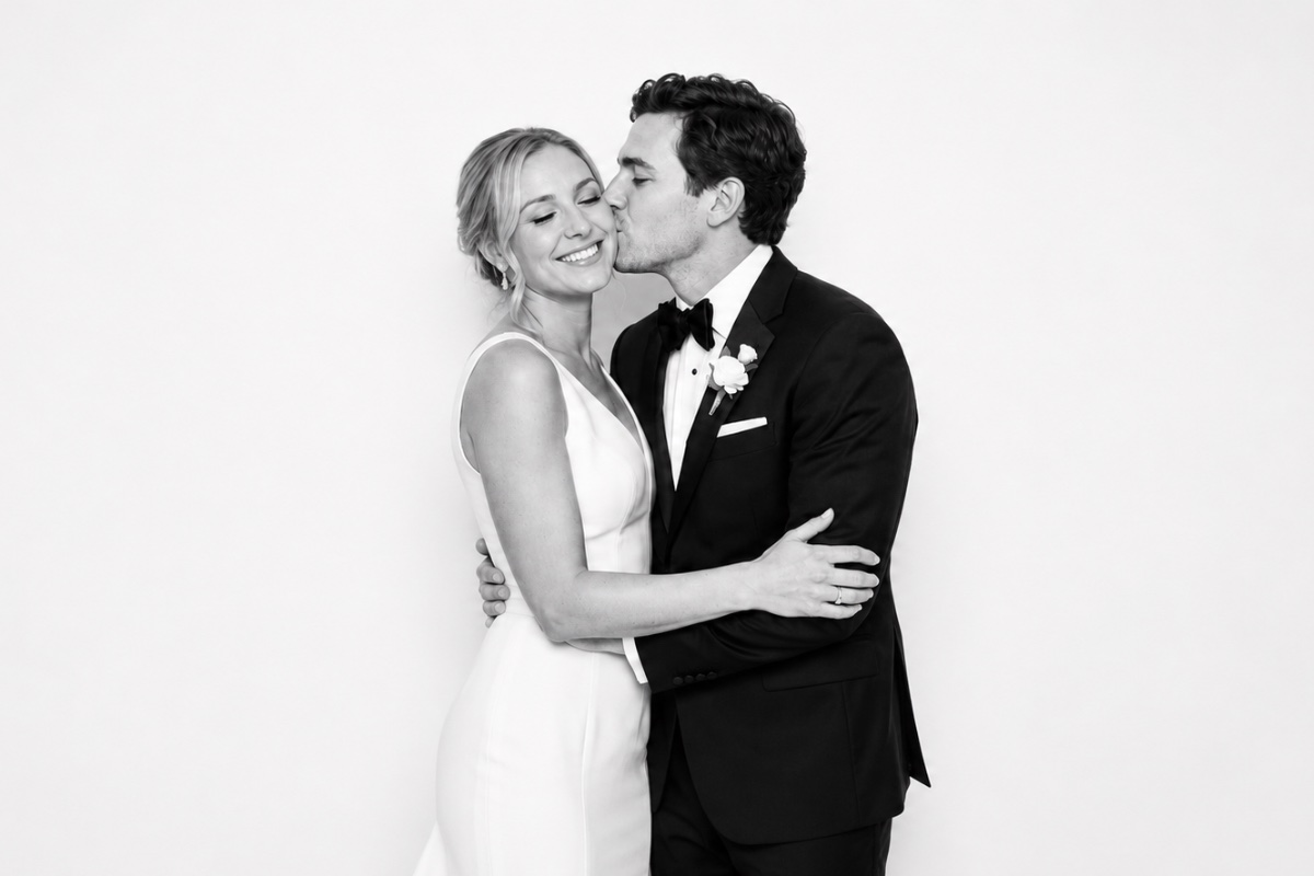 A groom kissing the bride's cheek, black and white
